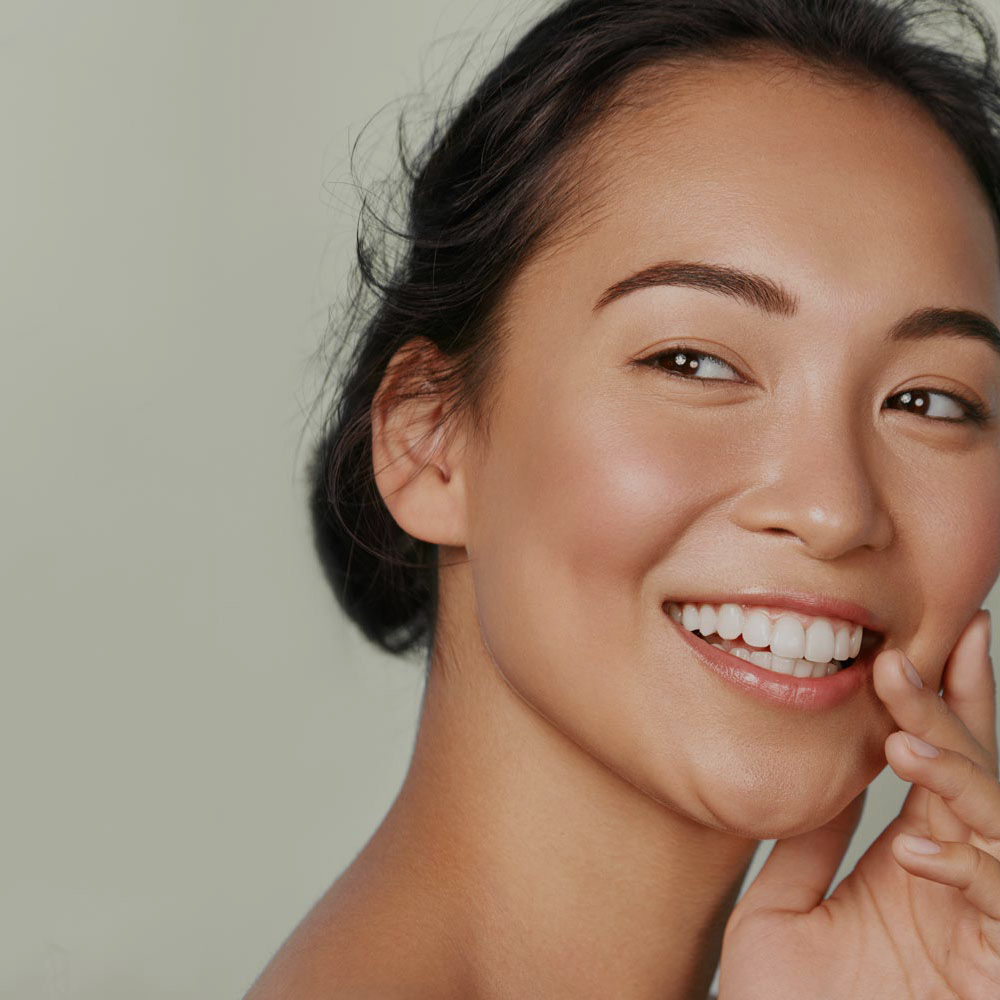 Beauty face. Smiling Asian woman touching healthy skin portrait.